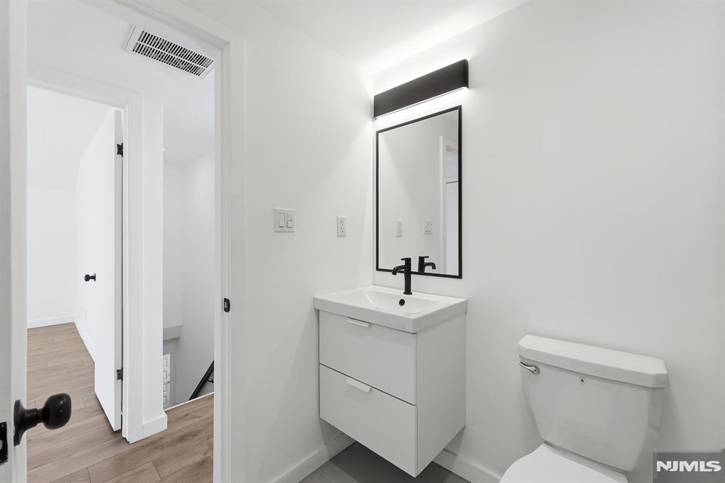 73 MacArthur Avenue Lodi, NJ 07644 - Photo 24 of 46 a bathroom with a toilet a sink and mirror