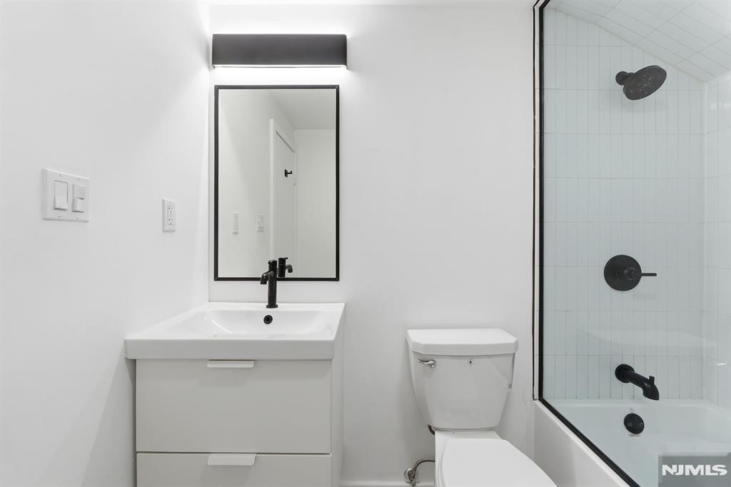 73 MacArthur Avenue Lodi, NJ 07644 - Photo 25 of 46 a bathroom with a sink a toilet a mirror and shower
