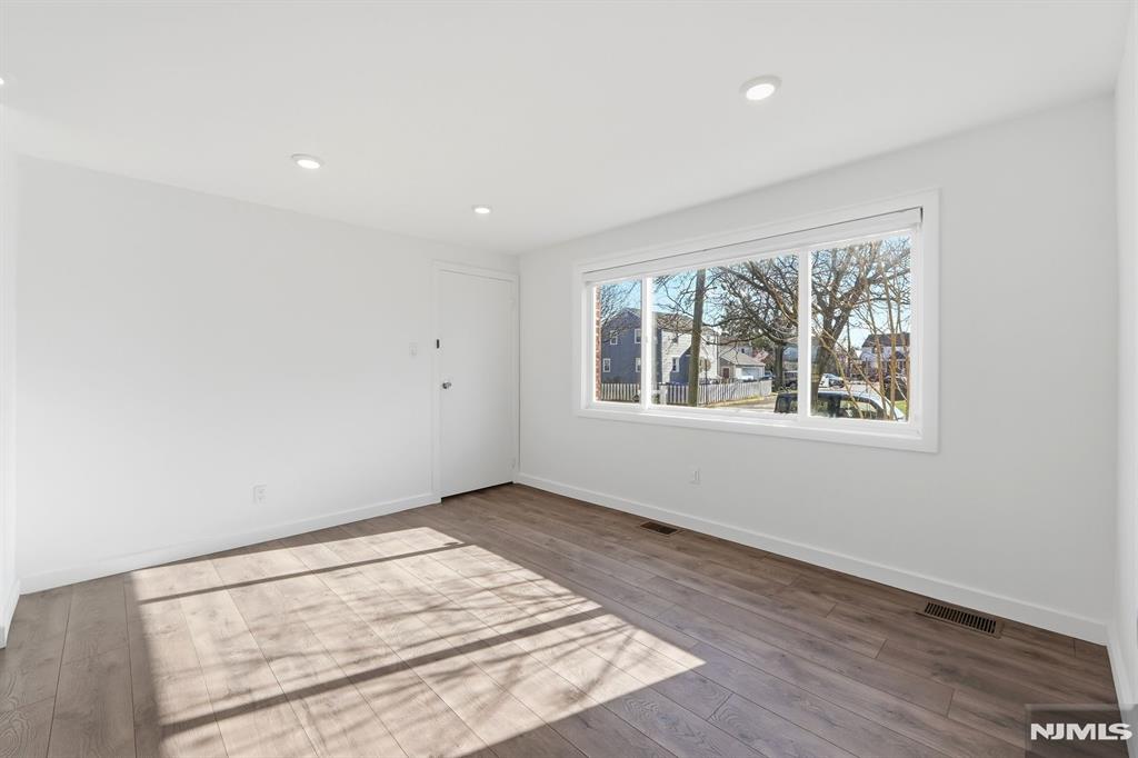73 MacArthur Avenue Lodi, NJ 07644 - Photo 3 of 46 an empty room with wooden floor and windows