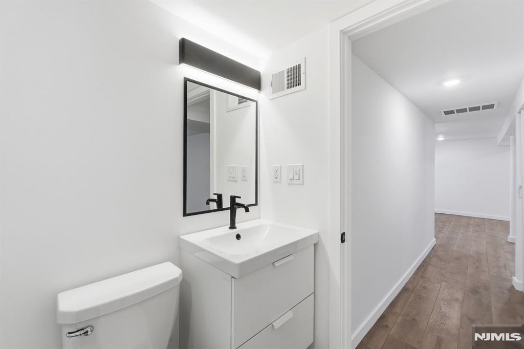 73 MacArthur Avenue Lodi, NJ 07644 - Photo 38 of 46 a bathroom with a toilet a sink and mirror