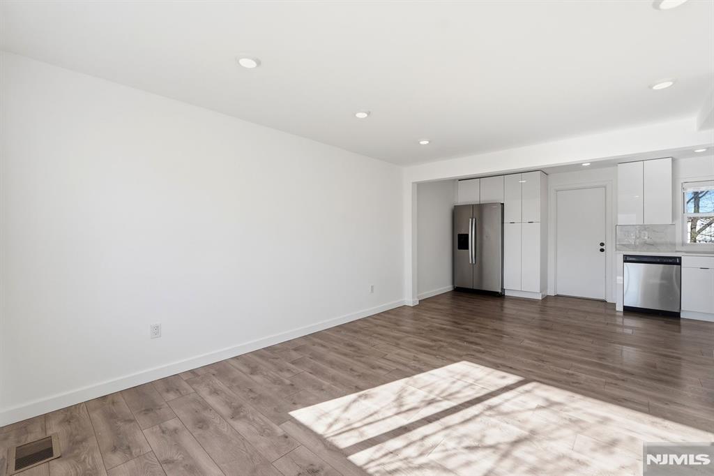 73 MacArthur Avenue Lodi, NJ 07644 - Photo 4 of 46 a view of an empty room with wooden floor and kitchen