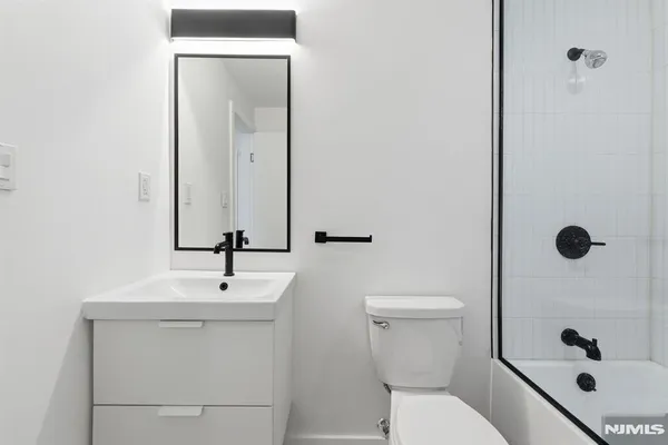 a bathroom with a sink a toilet a mirror and shower