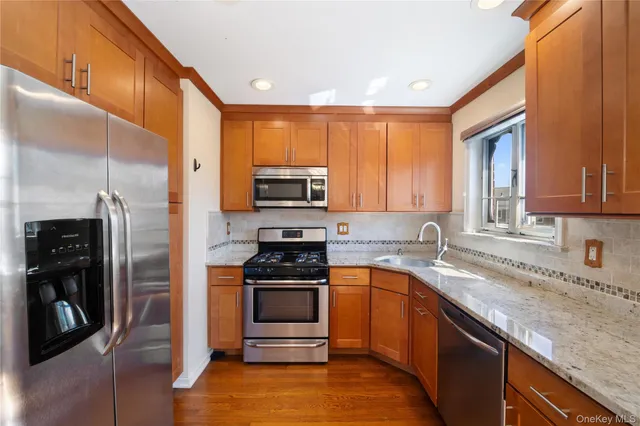 a view of a kitchen with kitchen island a refrigerator wooden floor and a sink