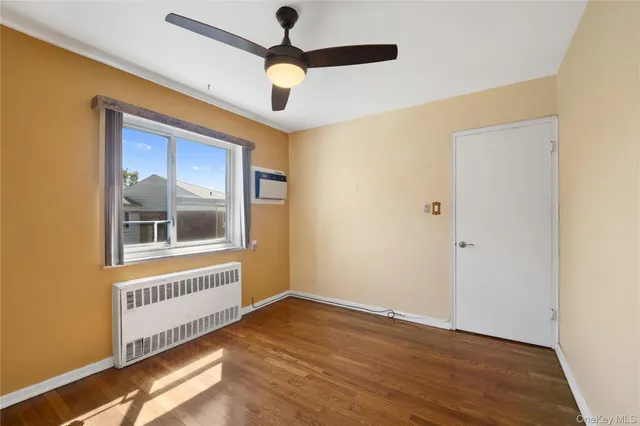 a view of an empty room with a window and wooden floor