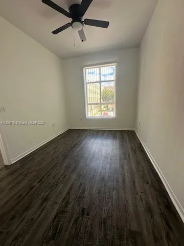 an empty room with wooden floor fan and windows