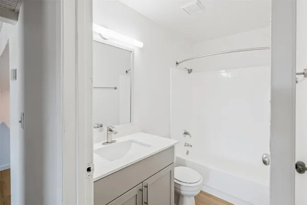a bathroom with a bathtub shower sink vanity mirror and toilet