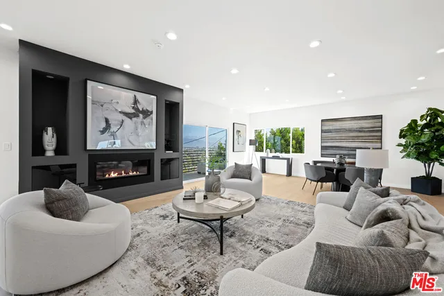 a living room with furniture a fireplace and a large window