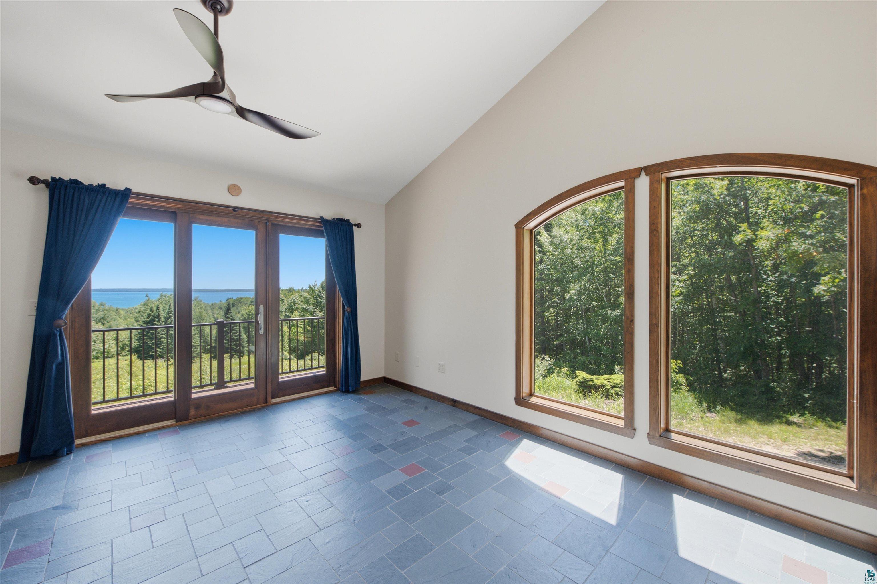 86270 Meyers-Olson Road Bayfield, WI 54814 - Photo 10 of 33 Vaulted ceiling with a contemporary ceiling fan, multiple large windows, and glass paneled doors opening to a balcony