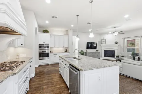 a large kitchen with kitchen island a stove a sink a refrigerator and a fireplace