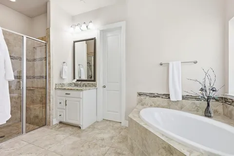 a spacious bathroom with a tub sink and mirror