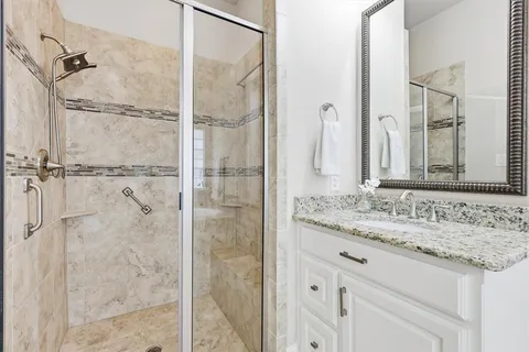 a bathroom with a granite countertop shower sink and mirror