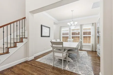 a dining room with wooden floor a chandelier a glass table and chairs