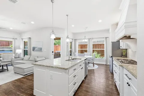 a large kitchen with kitchen island a stove a sink a dining table and chairs