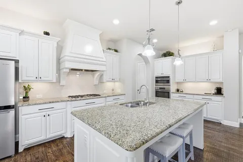 a kitchen with kitchen island granite countertop a sink a center island and cabinets