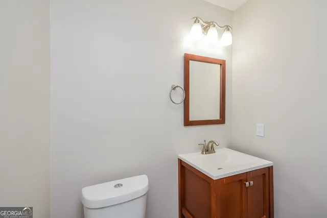 a bathroom with a toilet sink vanity and mirror