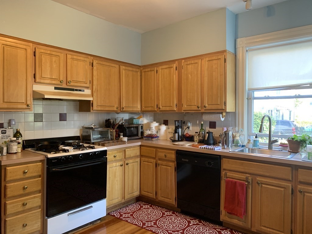 a kitchen with stainless steel appliances a sink a stove a refrigerator cabinets and a window
