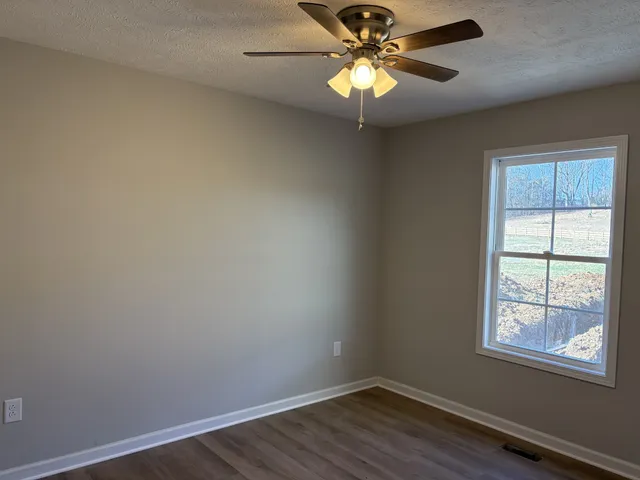 an empty room with a window and wooden floor