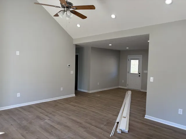 an empty room with wooden floor fan and windows