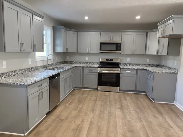 a kitchen with stainless steel appliances granite countertop a stove a sink dishwasher and a refrigerator