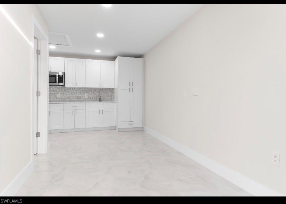 3202 8th Street Southwest Lehigh Acres, FL 33976 - Photo 15 of 21 Kitchen with white cabinetry, stainless steel microwave, recessed lighting, tasteful backsplash, and light stone counters