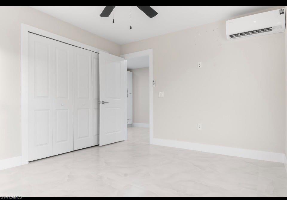3202 8th Street Southwest Lehigh Acres, FL 33976 - Photo 19 of 21 Unfurnished bedroom featuring a wall mounted AC, a ceiling fan, and a closet