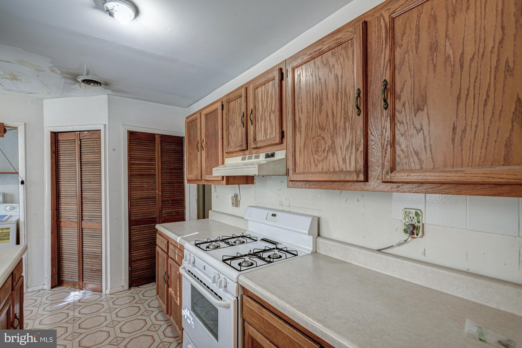 321 Bassett Avenue New Castle, DE 19720 - Photo 19 of 29 a kitchen with granite countertop a stove a sink dishwasher and a refrigerator with wooden cabinets