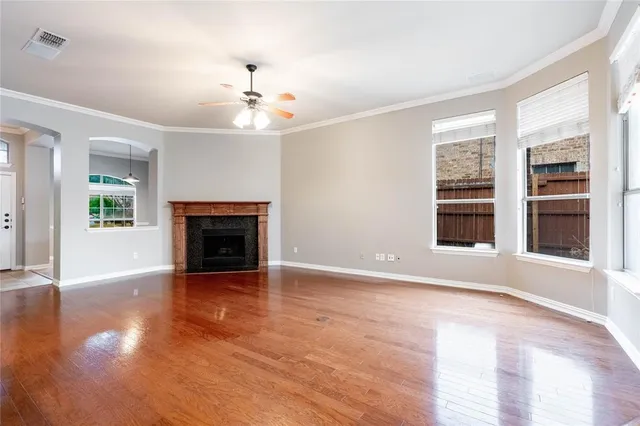 an empty room with wooden floor fireplace and windows