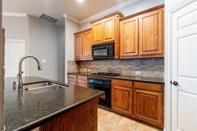 a kitchen with granite countertop a sink stainless steel appliances and cabinets