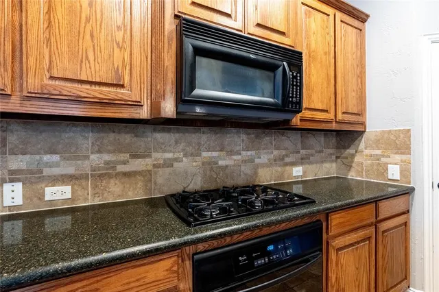 a kitchen with granite countertop cabinets stove top oven and microwave