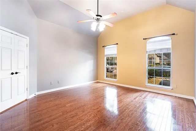 a view of an empty room with a window and wooden floor