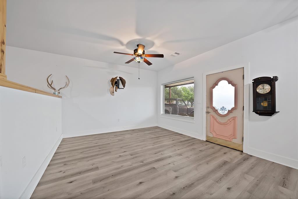 100 Shadle Ridge Court Poolville, TX 76487 - Photo 26 of 40 Spacious room with wood-finish flooring, a decorative entry door with a privacy glass insert, a ceiling fan, and a wide window