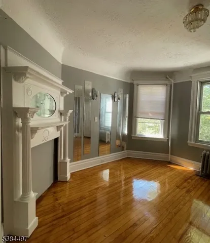 a view of an empty room with window and wooden floor