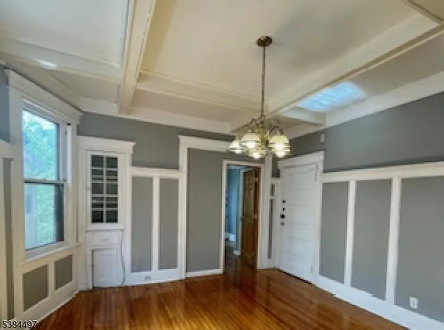 a view of a hallway with wooden floor and chandelier