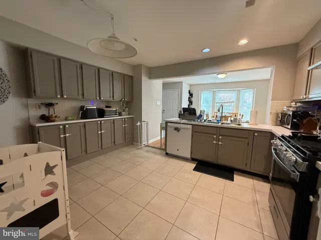 a kitchen with stainless steel appliances a sink a stove a refrigerator cabinets and a window