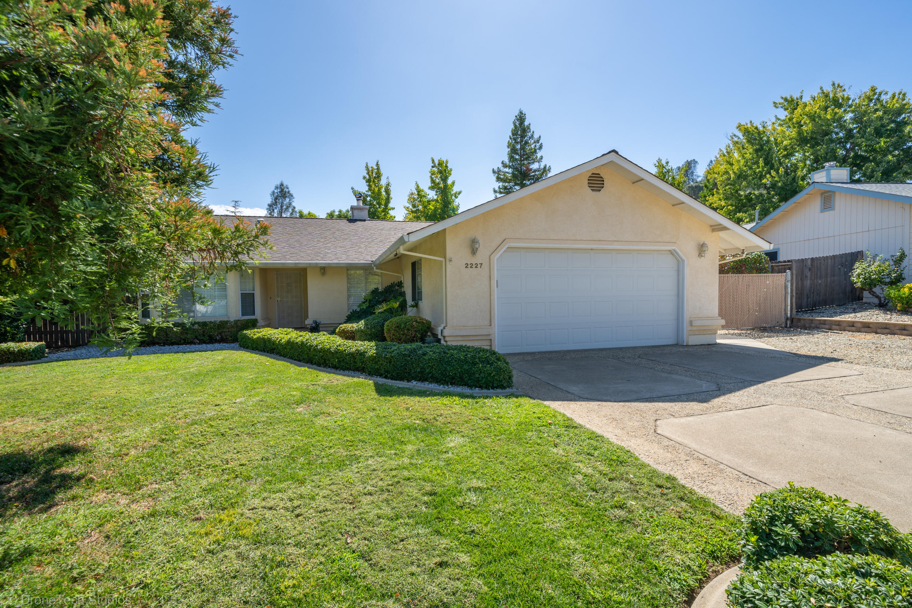 2227 Wicklow Street Redding, CA 96001 - Photo 6 of 90 a view of a white house next to a yard and a large tree