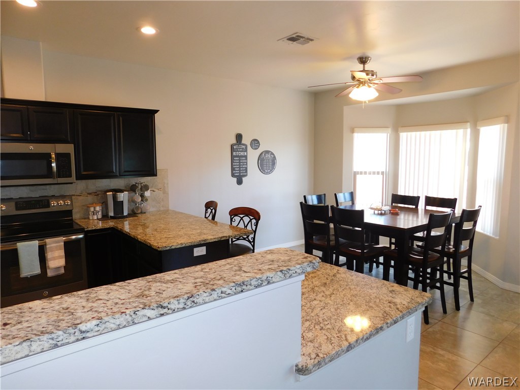 3370 South Ridge Avenue Bullhead City, AZ 86429 - Photo 28 of 56 a kitchen with stainless steel appliances granite countertop a stove a sink a dining table and chairs