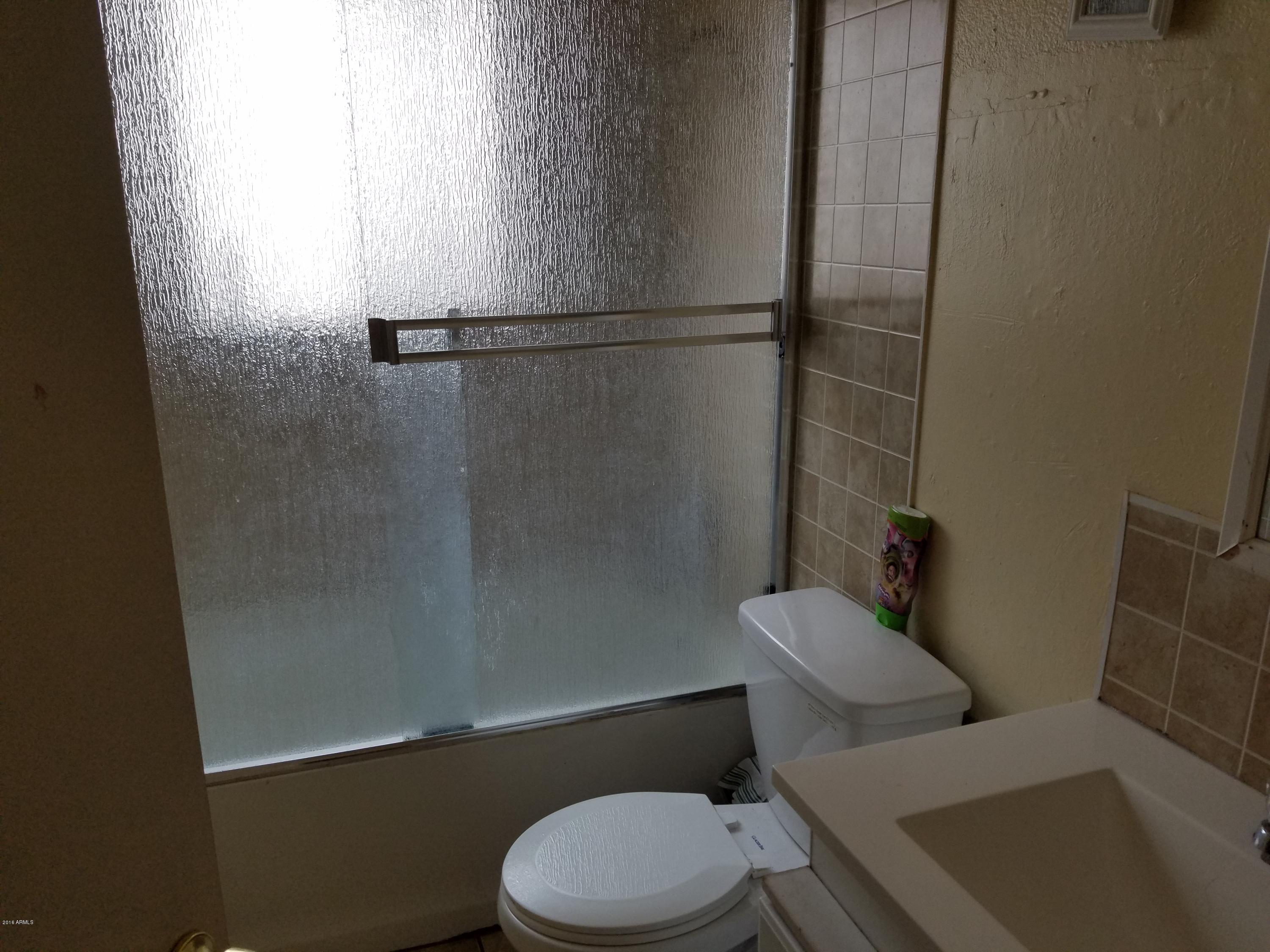 4939 West Berkeley Road Phoenix, AZ 85035 - Photo 29 of 60 a white toilet sitting next to a bath tub
