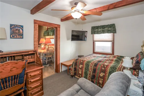 a bedroom with a bed a flat screen tv and a window