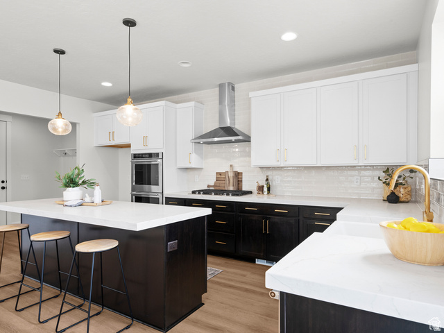1711 West Canyon Rim Road North Lehi, UT 84048 - Photo 7 of 31 Kitchen featuring a large central island with seating, white countertops, two-tone cabinetry, stainless steel appliances, and wood-finish flooring