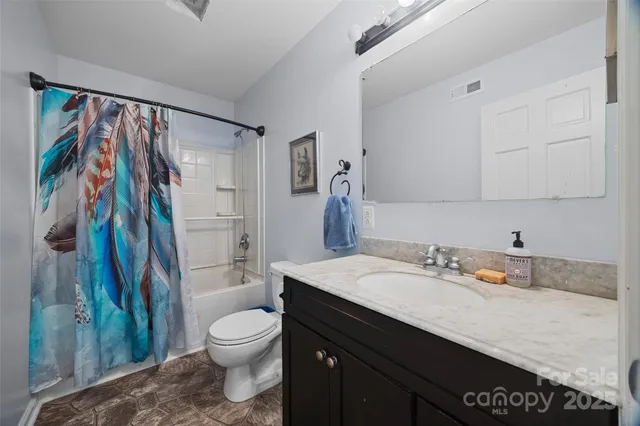 a bathroom with a granite countertop sink a toilet and a shower