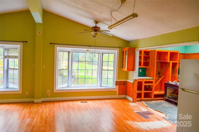 a view of an empty room with wooden floor and windows