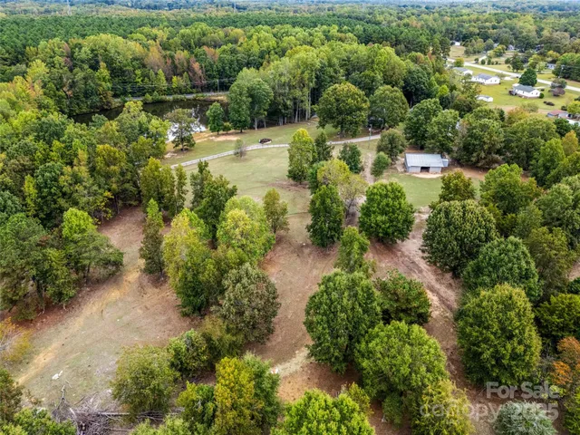 an aerial view of residential house with outdoor space and trees all around