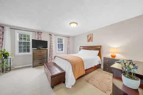 a spacious bedroom with a bed and wooden floor