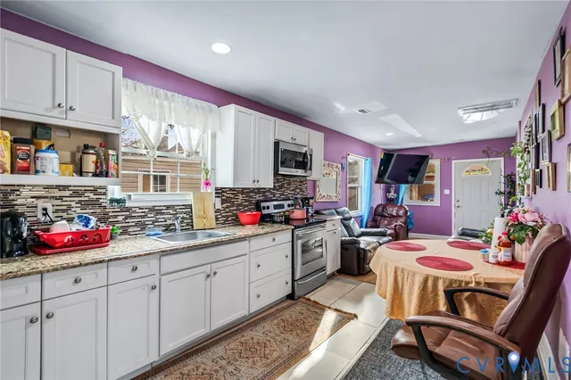 a kitchen with granite countertop lots of clutter and stainless steel appliances