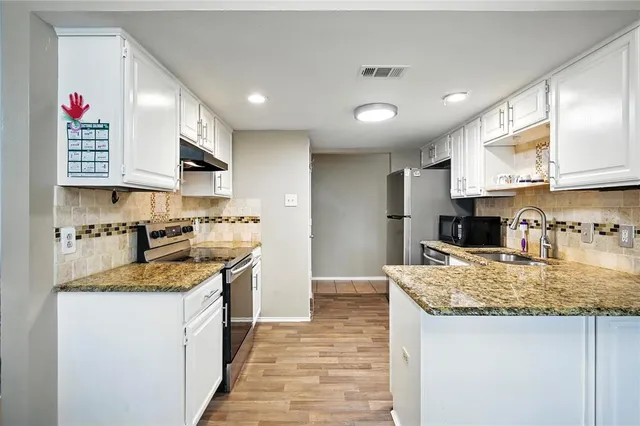 a kitchen with stainless steel appliances granite countertop a sink dishwasher and a refrigerator