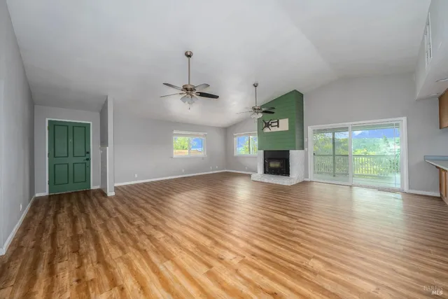 a view of a livingroom with wooden floor a ceiling fan and window