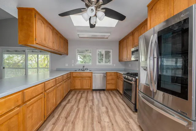 a large kitchen with stainless steel appliances granite countertop a large window and a sink