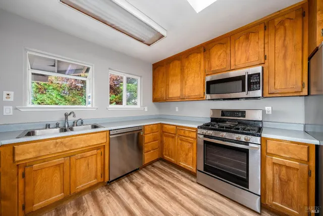 a kitchen with stainless steel appliances a stove sink microwave and cabinets