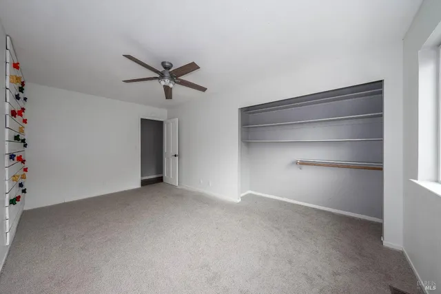 a view of an empty room with a ceiling fan and a window