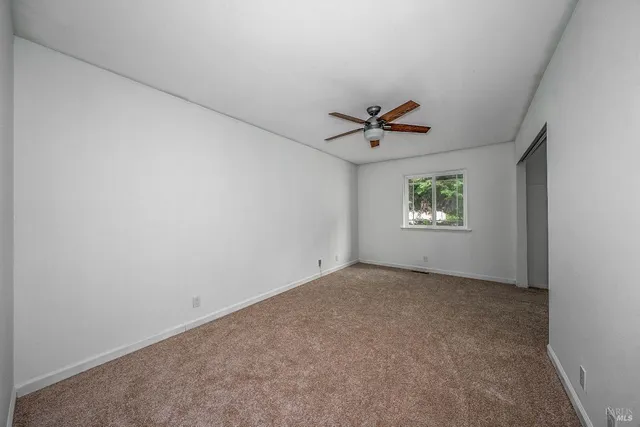 an empty room with a window and a ceiling fan